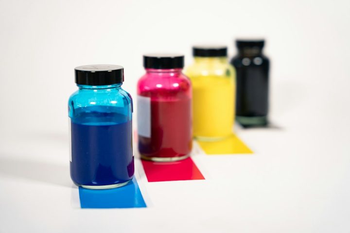 Botellas de tinta cian, magenta, amarilla y negra sobre fondo claro